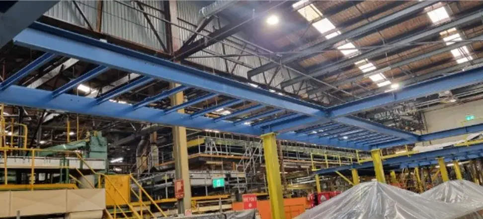 Blue steel platform beams and cross members supported on yellow columns inside an industrial facility
